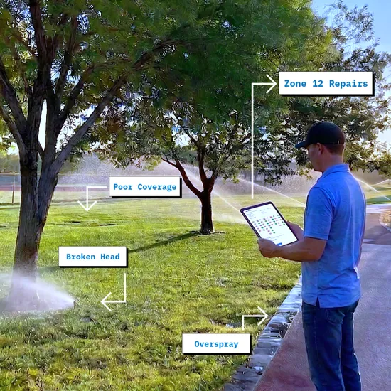 An irrigation technician recording a checkup on a tablet while sprinklers run, with faults labelled on site: a broken head, poor coverage, overspray, and repairs logged against Zone 12.